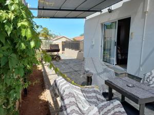 a patio with two benches and a table on a house at Come Home in Oudtshoorn Self-Catering Units in Oudtshoorn