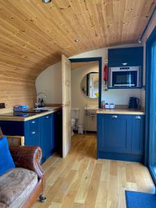 a kitchen with blue cabinets and a wooden ceiling at Robin's Nest (Top Cabin) in Foolow