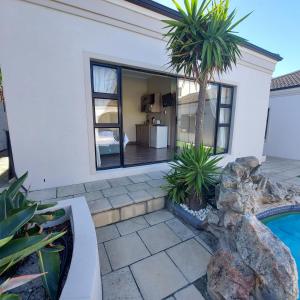 a house with a palm tree and a swimming pool at Balmoral Cottage, West Beach in Cape Town