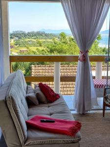 d'un salon avec un canapé et une grande fenêtre. dans l'établissement Apartamento Praia da Gamboa - Cabanas da Candoca Vista para o Mar, à Garopaba