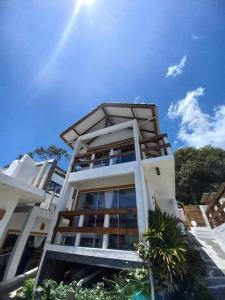 un grand bâtiment blanc avec le soleil au ciel dans l'établissement Apartamento Praia da Gamboa - Cabanas da Candoca Vista para o Mar, à Garopaba