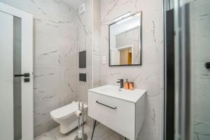 a white bathroom with a sink and a mirror at Style apartment studio Kabeny in Michalovce