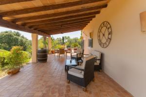 a patio with chairs and a clock on the wall at Finca Vallaca in Calonge