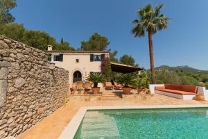 a house with a swimming pool and a stone wall at Finca Vallaca in Calonge