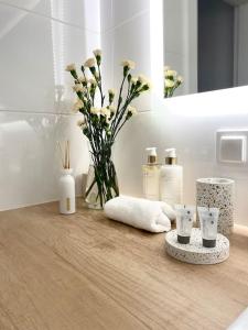 - un comptoir de salle de bains avec des serviettes et un vase de fleurs dans l'établissement Ultra Apartments Kamienica Nova II, à Szczecin