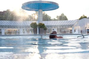 una persona en una piscina con una fuente en Aqua Blu Hotel, en Bad Füssing