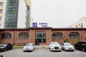 un gruppo di auto parcheggiate di fronte a un edificio di AMINA HOTEL a Astana