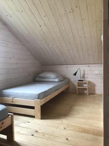 Cama en habitación con techo de madera en Domki Perełka en Mielenko