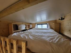 Cama en habitación de madera con ventana en TinyHouse Rossas, en Santa Comba de Rossas