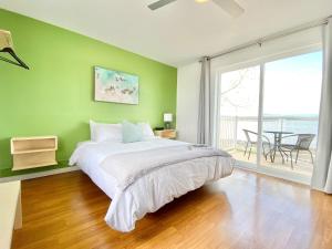 a green bedroom with a bed and a large window at La Plage Motel in Berthier-sur-Mer