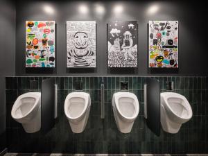 vier Urinale in einem Bad mit Bildern an der Wand in der Unterkunft URBAN LOFT Berlin in Berlin