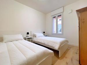 2 Betten in einem weißen Zimmer mit Fenster in der Unterkunft UR NEST San Giorgio in Bologna