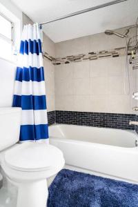 a bathroom with a white toilet and a blue and white shower curtain at Perfectly Situated 2-BR Residential Home in Largo- Close to Beach and everything!! in Largo