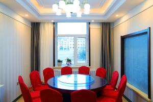 una sala de conferencias con mesa y sillas rojas en Yabuli Hot Spring Health Center Hotel, en Shangzhi