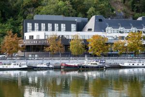 那慕尔Mercure Namur Hotel的一群船停靠在酒店前面的水面上