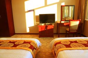 Habitación de hotel con 2 camas y TV de pantalla plana. en Yabuli Hot Spring Health Center Hotel, en Shangzhi