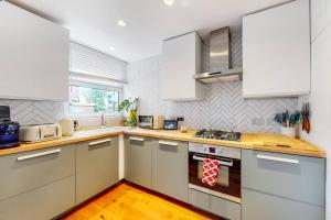a kitchen with white cabinets and a stove top oven at Charming 2-bedroom maisonette with private garden in London