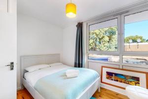 a bedroom with a bed and a large window at Charming 2-bedroom maisonette with private garden in London