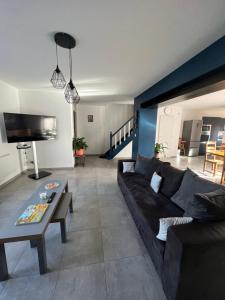 a living room with a black couch and a table at Le Séjour qu'on M in Le Cateau