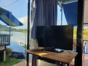 a flat screen tv sitting on a table with a window at บ้านสวนริมน้ำเขาค้อ in Khao Kho