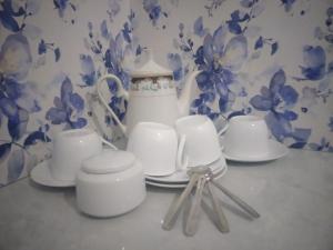 a table topped with white cups and plates and a vase at freedom house in Unawatuna