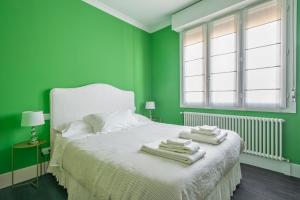 Un dormitorio verde con una cama con toallas. en Green House city center en Bolonia