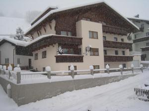 ein schneebedecktes Gebäude mit einem Zaun davor in der Unterkunft Haus Birgit in Pettneu am Arlberg