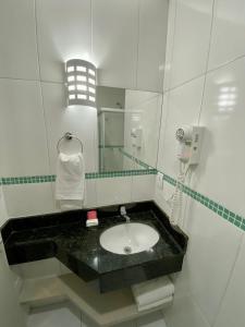 a bathroom with a sink and a mirror at Coral Hotel - Próximo a PUCRS in Porto Alegre