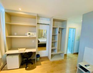 a room with a desk and shelves and a bed at Coral Hotel - Próximo a PUCRS in Porto Alegre