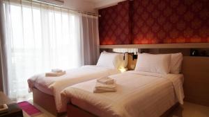 two beds in a hotel room with towels on them at Kavin Buri Green Hotel in Udon Thani