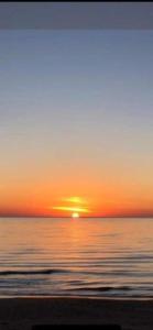 un tramonto sull'oceano con il sole che tramonta sull'acqua di Appartamento sul mare Scoglitti 2 a Scoglitti