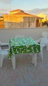 un tavolo con sedie e una tovaglia verde e bianca di Appartamento sul mare Scoglitti 2 a Scoglitti