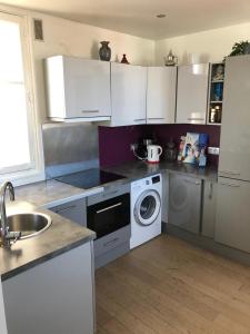 a kitchen with white cabinets and a washing machine at Logement de standing à 9min du centre de Paris in Colombes