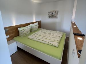 um pequeno quarto com uma cama verde num quarto em FeWo Furtwangen em Furtwangen