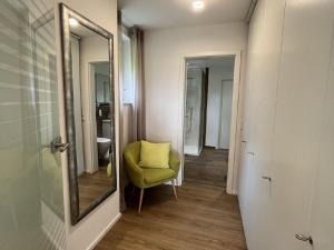 a hallway with a yellow chair and a mirror at FeWo Furtwangen in Furtwangen