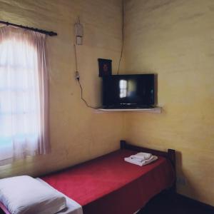 a room with two beds and a tv and a window at Los Zarzos in Mina Clavero