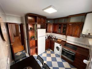 a kitchen with wooden cabinets and a white refrigerator at MoMA Meanas Aviles Centro in Avilés