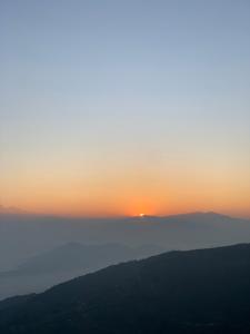 einen Sonnenuntergang über den Bergen mit Sonnenuntergang in der Ferne in der Unterkunft Nagarkot Trekkers Inn in Nagarkot