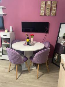 een eetkamer met een witte tafel en paarse stoelen bij Studio Apartman Jovičić in Bjelovar