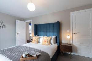 a bedroom with a large bed with a blue headboard at Elliot Oliver - Luxurious Two Bedroom Apartment With Parking in Gloucester