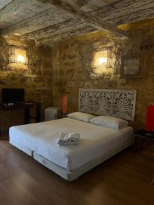 una camera da letto con un grande letto bianco su un muro di pietra di Experience Museum a Agrigento