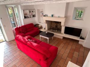 ein Wohnzimmer mit zwei roten Sofas und einem Kamin in der Unterkunft La maison Mortisson in Saint-Rémy-de-Provence