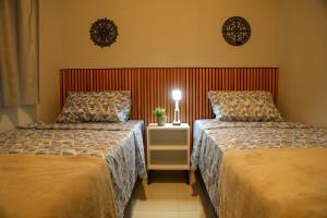 a hotel room with two beds and a night stand at Casa Pequena, Completa e Aconchegante - Tiny House in Palmas