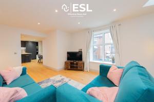 a living room with a blue couch and a television at High Quality 2 Bedroom Church Apartment with Free Parking in Shrewsbury