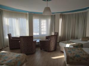 a hotel room with two beds and chairs and windows at Cender Hotel in Antalya