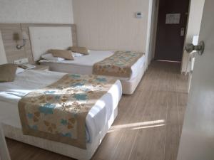 um quarto de hotel com três camas e uma porta em Cender Hotel em Antalya
