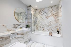 a bathroom with a tub and a sink and a mirror at Elliot Oliver - Stunning Three Bedroom Penthouse With Large Terrace & Parking in Gloucester +19 photos