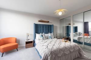 een slaapkamer met een groot bed en een oranje stoel bij Elliot Oliver - Stunning Three Bedroom Penthouse With Large Terrace & Parking in Gloucester