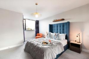 a bedroom with a large bed with a blue headboard at Elliot Oliver - Stunning Three Bedroom Penthouse With Large Terrace & Parking in Gloucester
