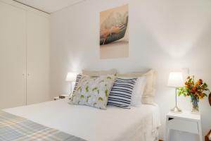 a white bedroom with a bed and a vase of flowers at Casa da Praça Apartments - by Casas na Ilha in Funchal